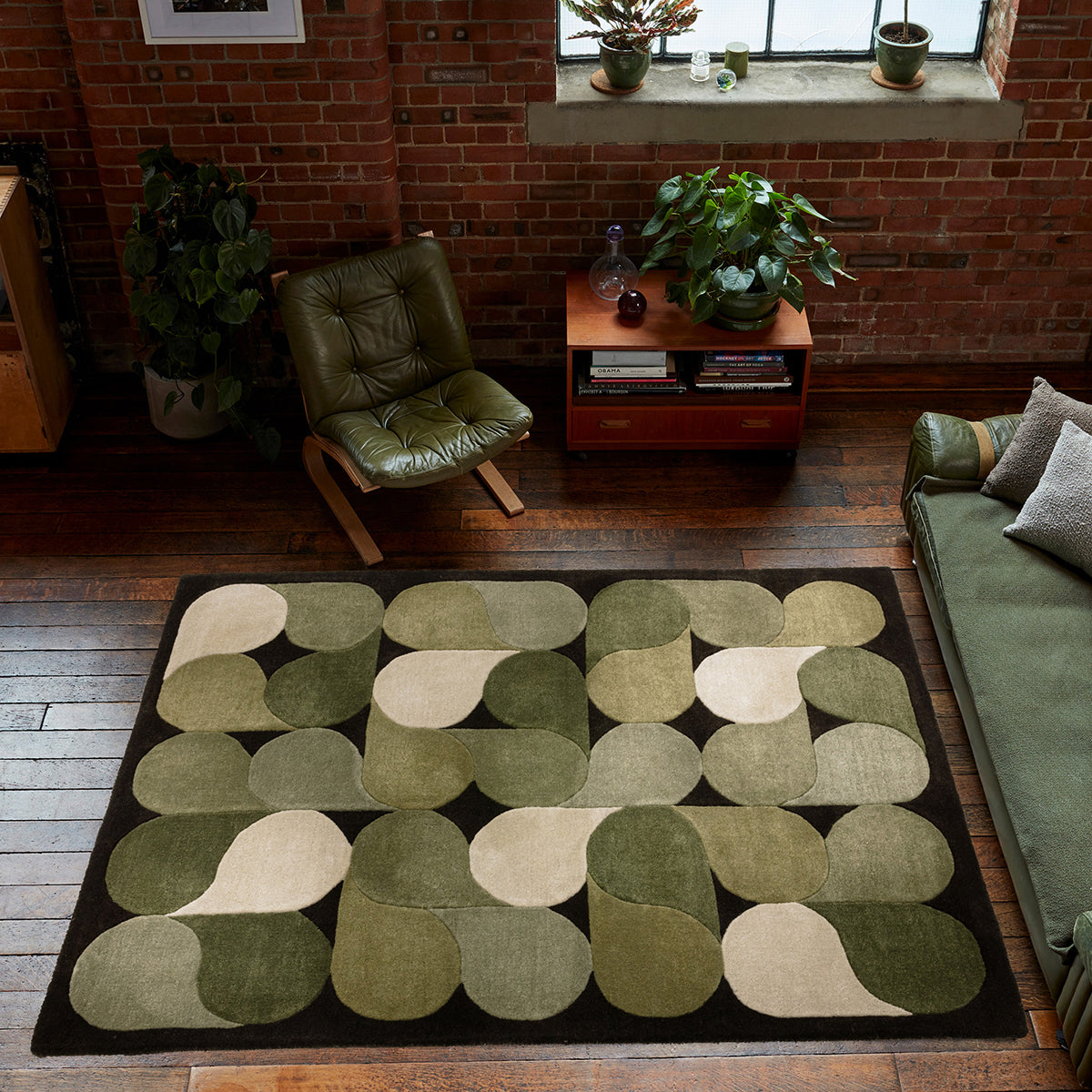 Living room with a green and beige patterned rug, green chair, and sofa.