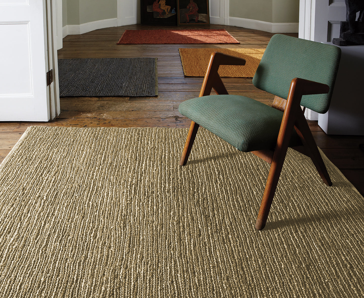Green chair on a textured rug with wooden floor and door in the background