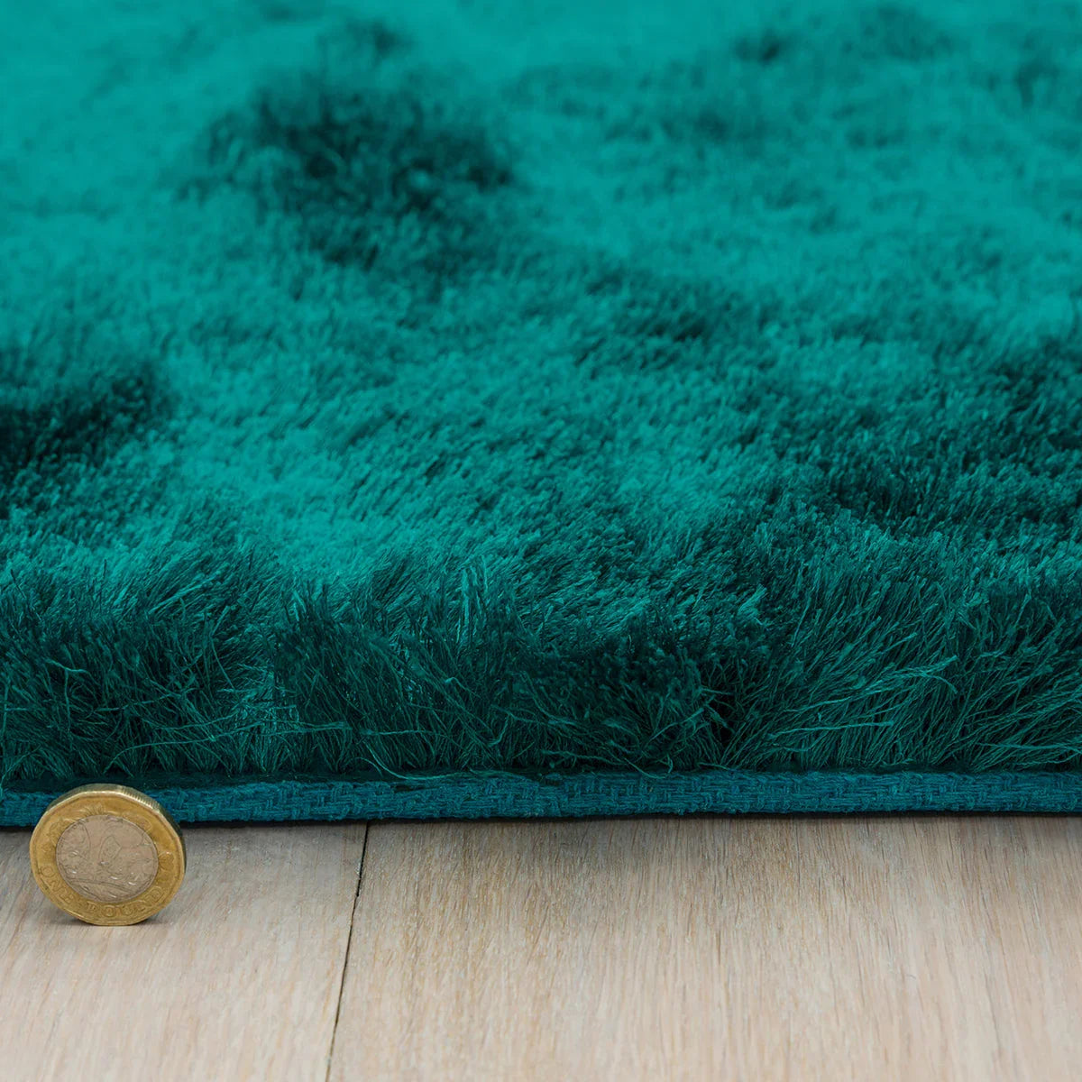Asiatic Whisper Dark Teal Rug featuring shaggy high-pile texture in dark teal, teal and emerald on light wood floor, hand-tufted polypropylene
