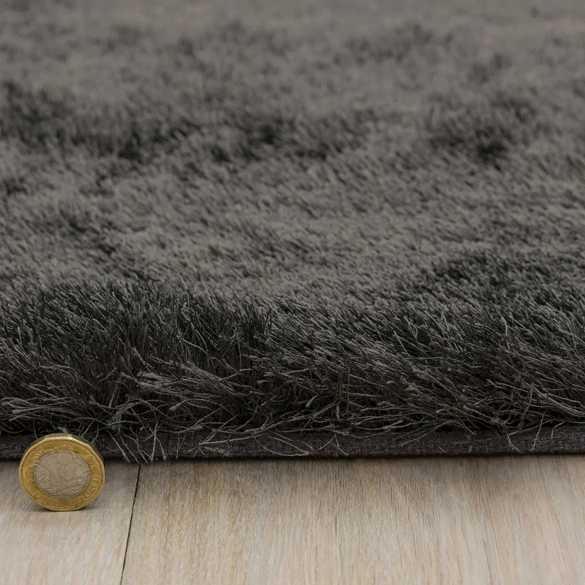 Asiatic Whisper Graphite Designer Rug featuring shaggy pile in graphite grey and charcoal on light wood floor, hand-tufted wool