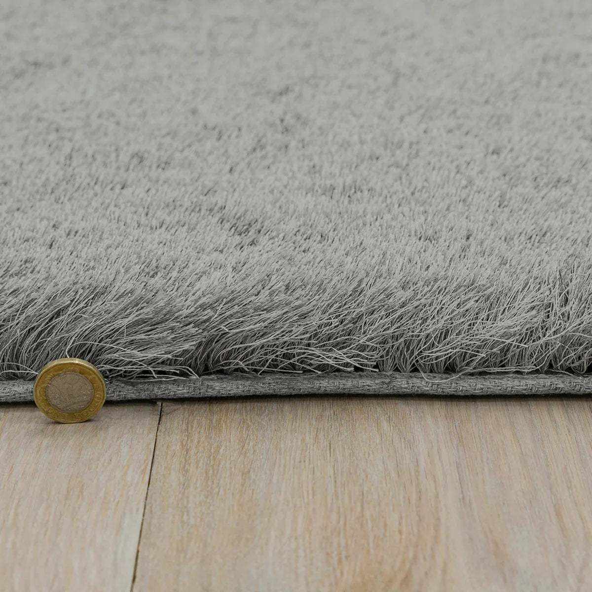 Asiatic Whisper Tungsten Designer Rug featuring shaggy pile in tungsten grey on warm wood background, machine-loomed wool