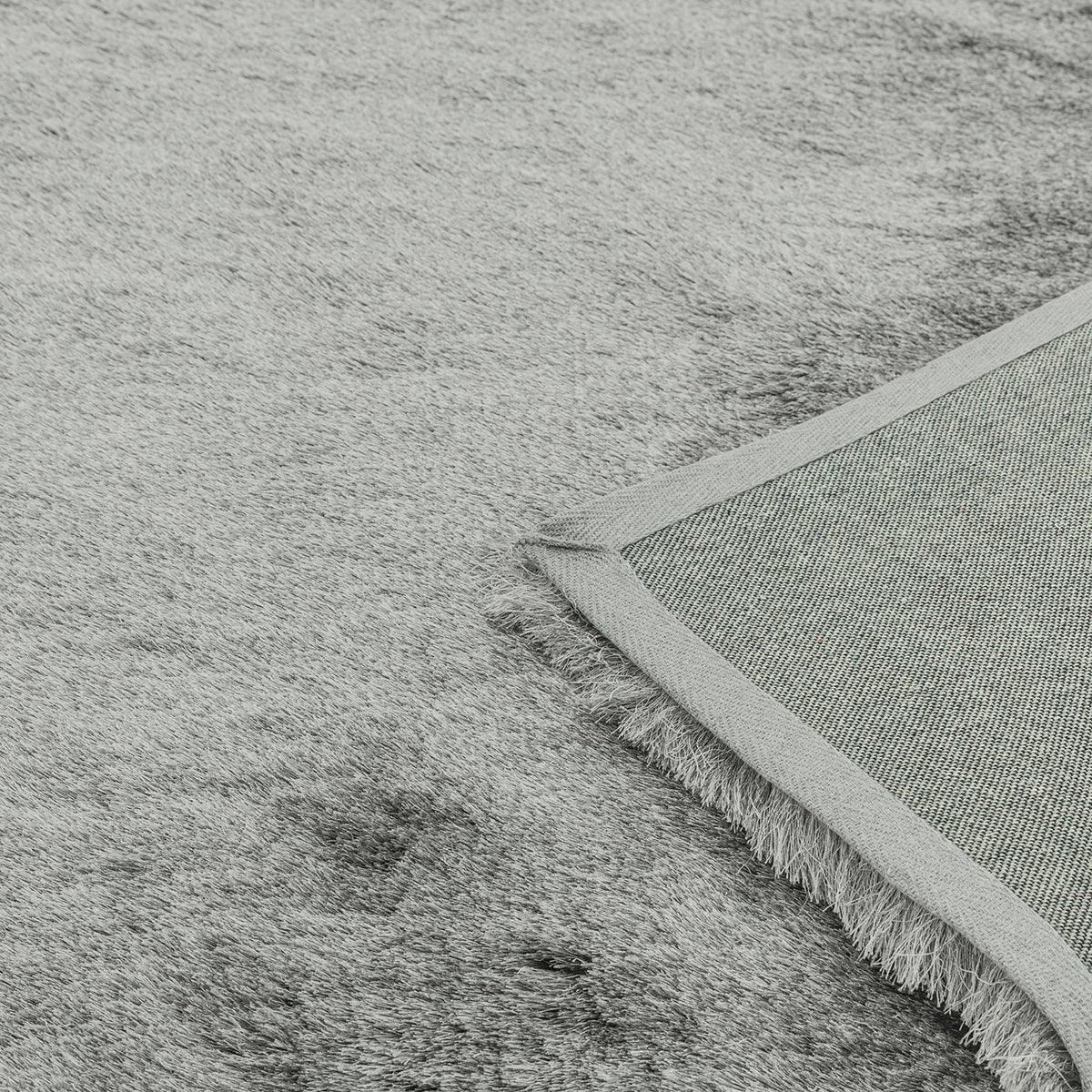 Asiatic Whisper Tungsten rug featuring soft textured weave with fringe in tungsten grey on pale grey backing.