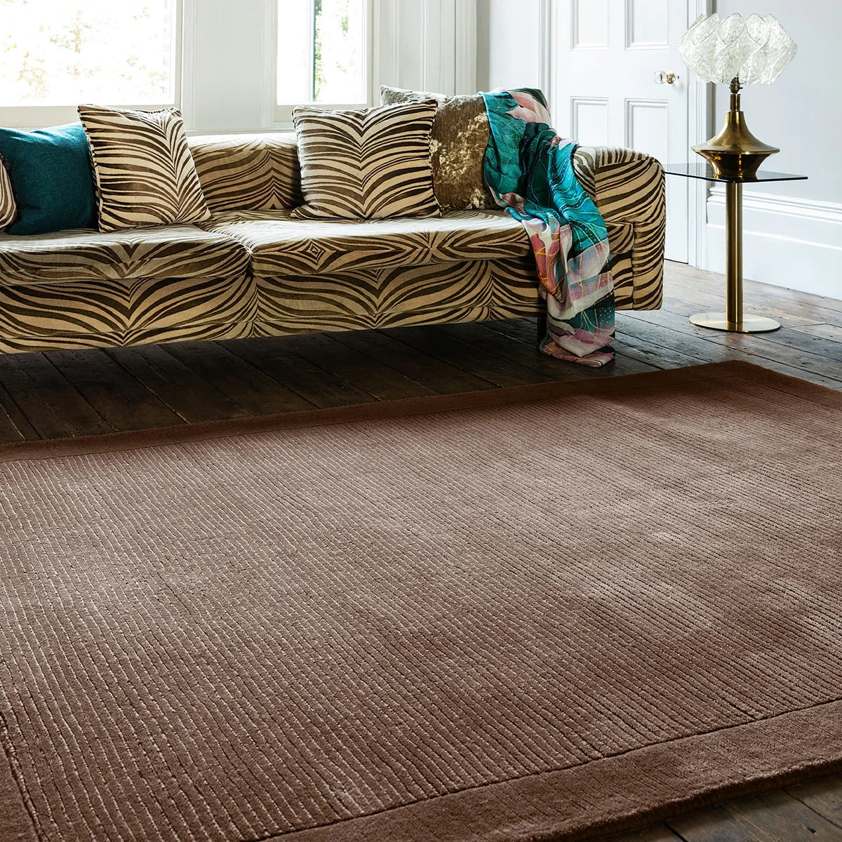 Brown textured rug in a living room with a patterned sofa and decorative items.