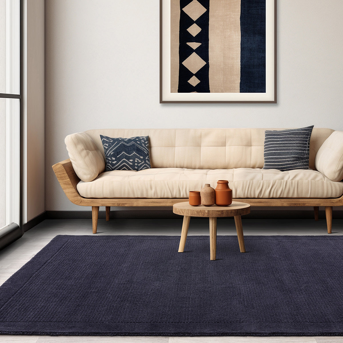 Beige sofa with blue pillows in a living room setting with a dark blue rug and wooden coffee table.