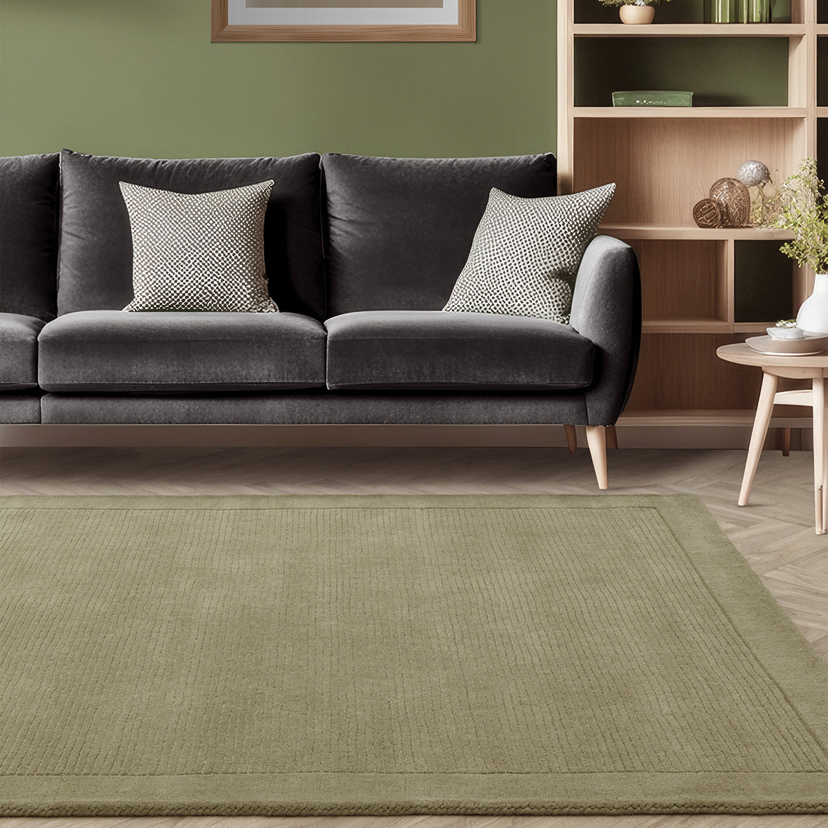 Gray sofa with patterned cushions in a living room setting with a green rug.