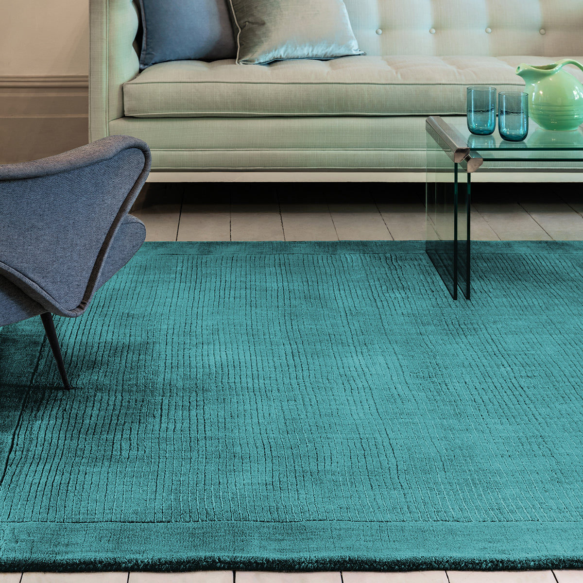 Teal rug in a living room with a sofa, chair, and coffee table.