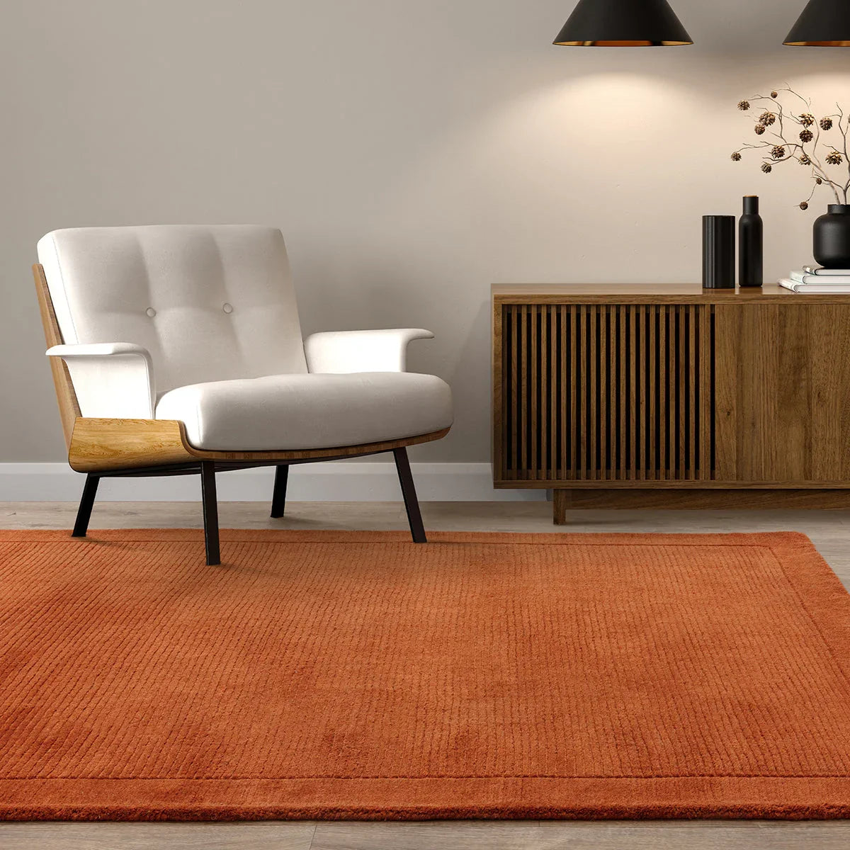 Modern living room with a white armchair, wooden sideboard, and orange rug.