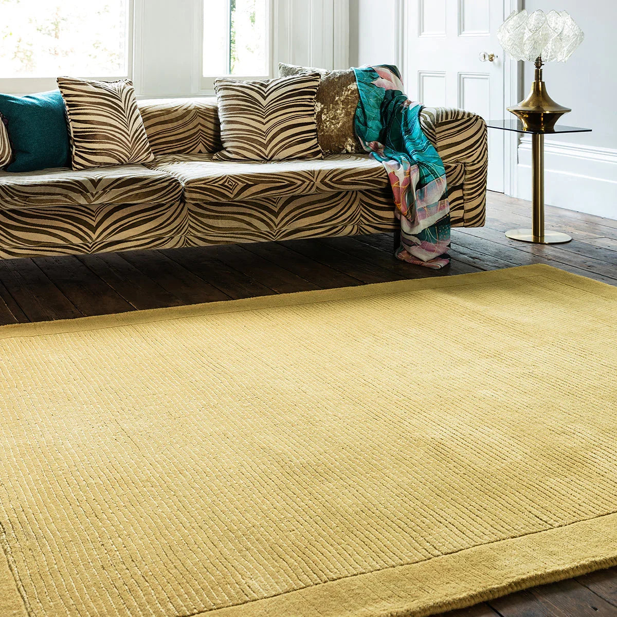 Living room with a patterned sofa and a textured yellow rug.
