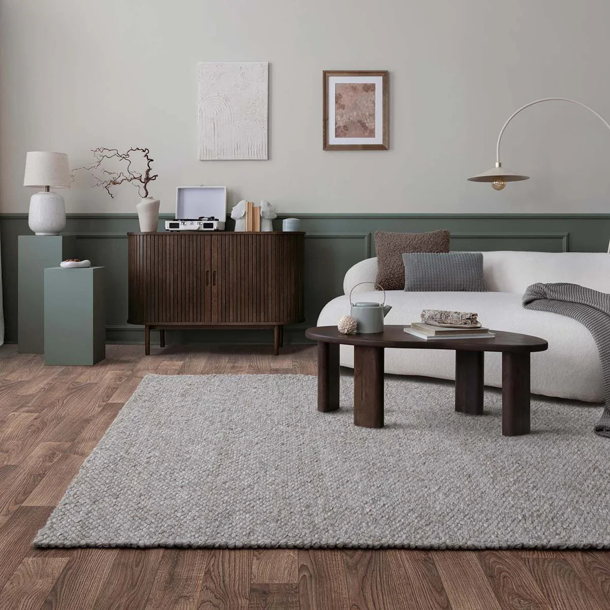 Modern living room with a gray rug, wooden coffee table, and white sofa.