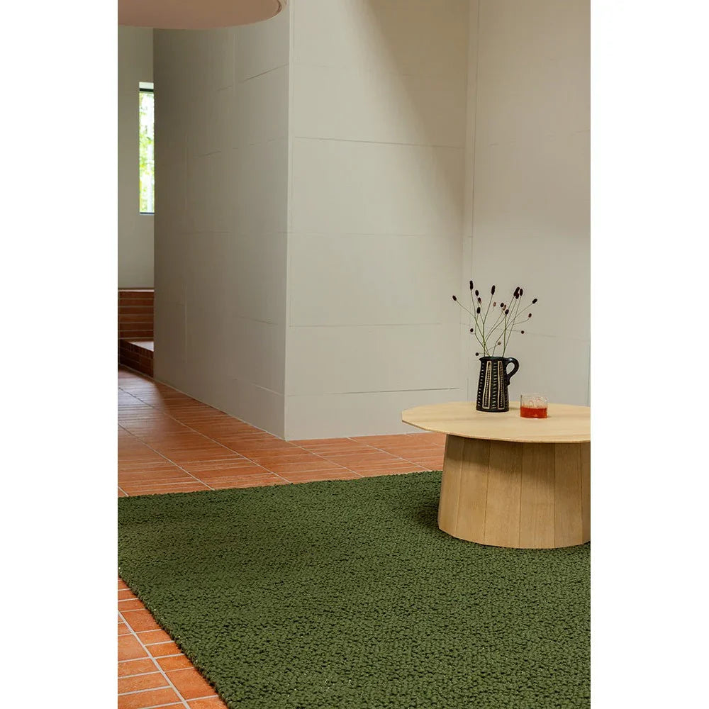 Brink & Campman Bond Moss Designer Rug featuring textured shag in moss green on warm terracotta tile background, hand-tufted wool