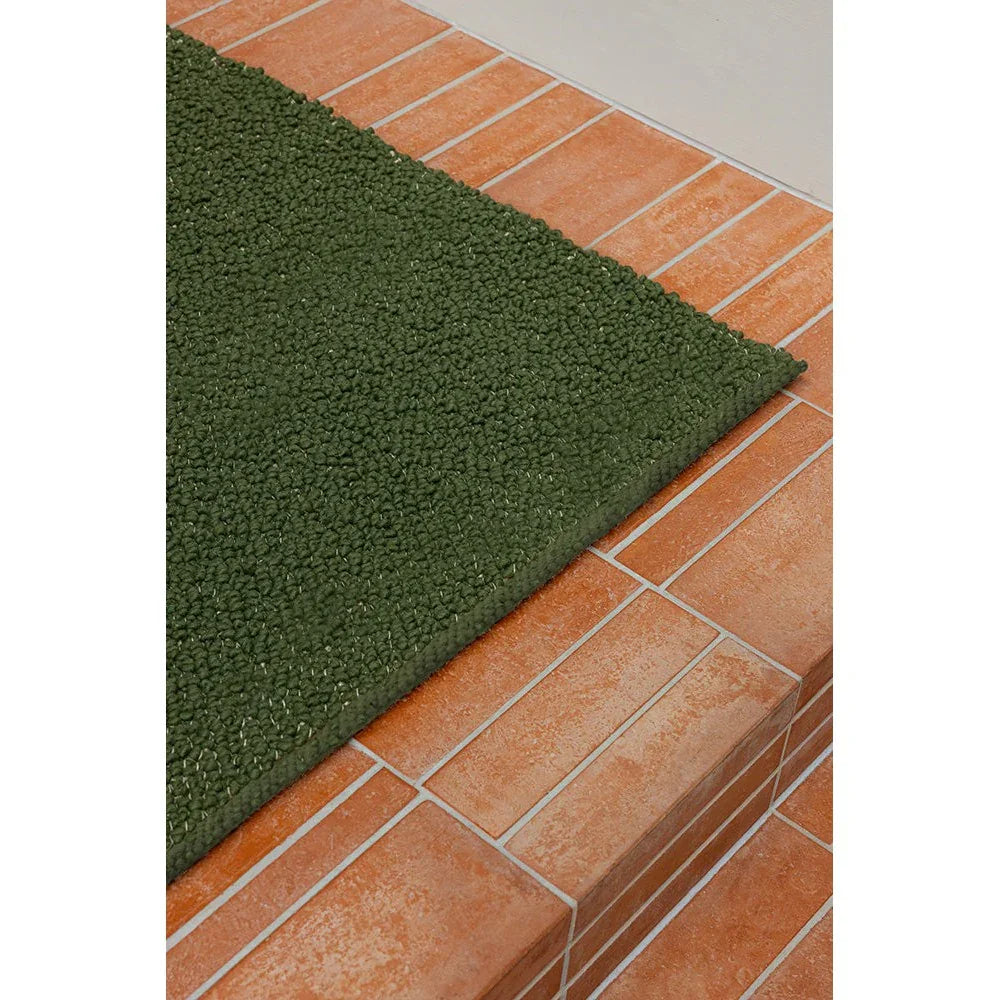 Brink & Campman Bond Moss Designer Rug featuring moss-green shag texture on terracotta tile background, hand-tufted wool