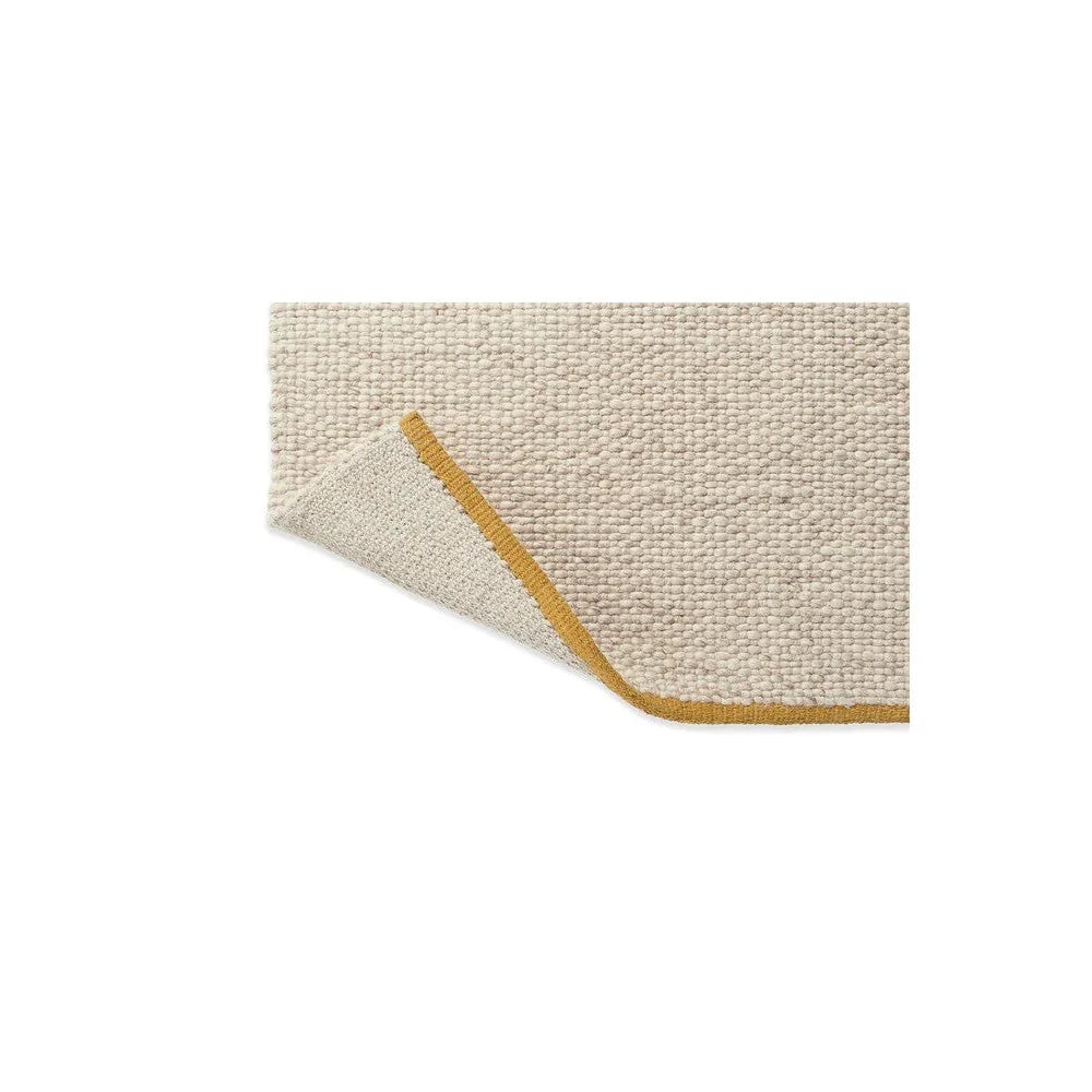 Brink & Campman Craft Matter plain rug featuring solid texture in warm white with mustard edge on white background, construction not specified, material not specified