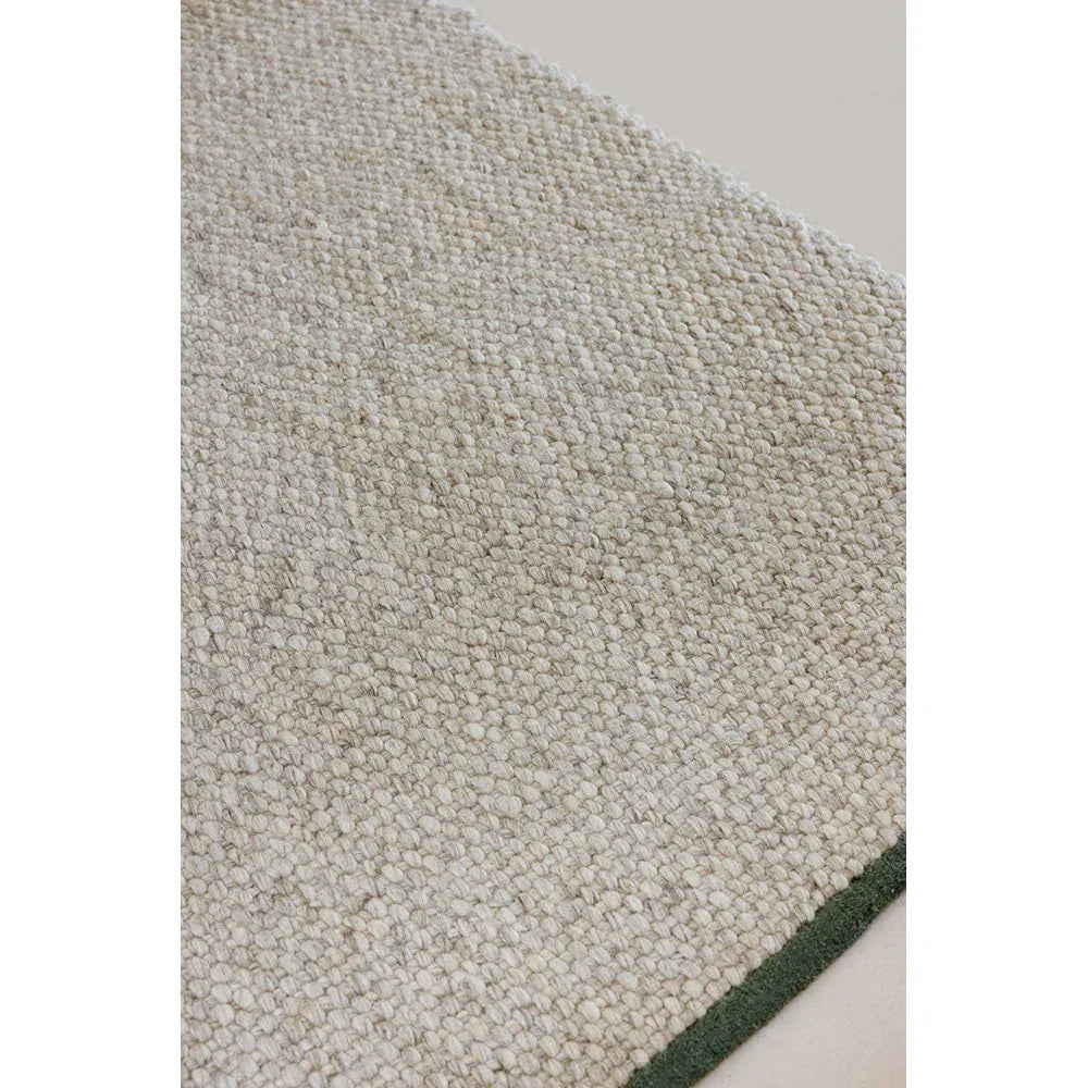 Brink & Campman Craft Matter Ash Grey Rug featuring textured boucle pattern with dark green border on light background, hand-tufted wool