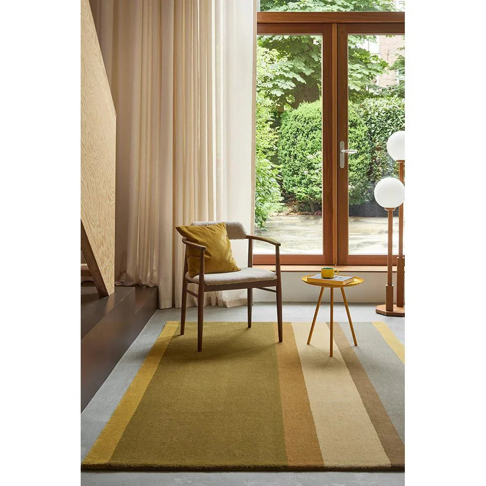 B&C Decor Linear Earth Rug featuring linear stripe in ochre, mustard, beige and tan on light grey floor, hand-tufted wool