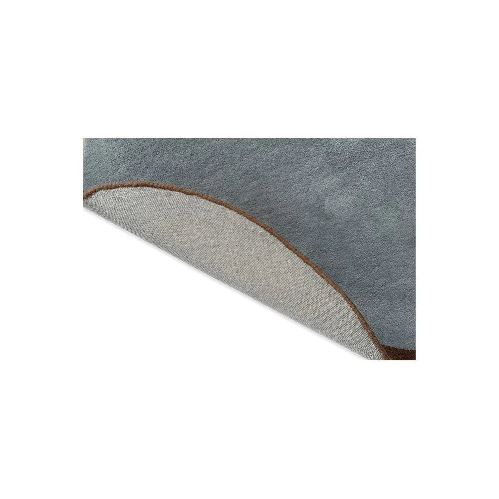 Brink & Campman Element Chad Brown Blue Designer Rug featuring abstract wave design in blue-grey, beige with brown edge on white background, hand-tufted wool