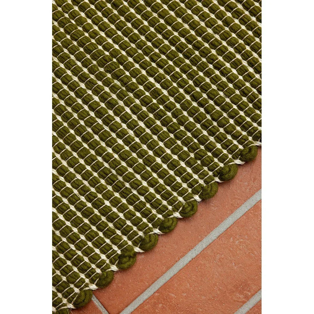 Brink & Campman Frame Leaf Rug featuring braided lattice in olive and moss greens on terracotta floor, hand-loomed wool