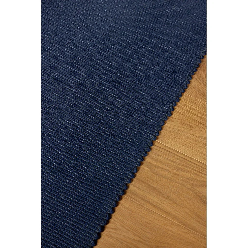 Brink & Campman Grid Ink Designer Rug featuring grid pattern in navy ink on warm brown wooden floor, hand-tufted wool
