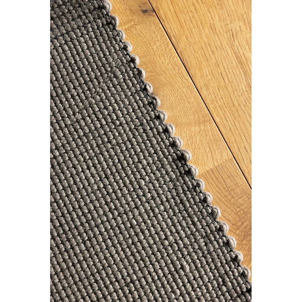 Brink & Campman Grid Stone Designer Rug featuring textured grid pattern in charcoal grey and stone on warm oak floor