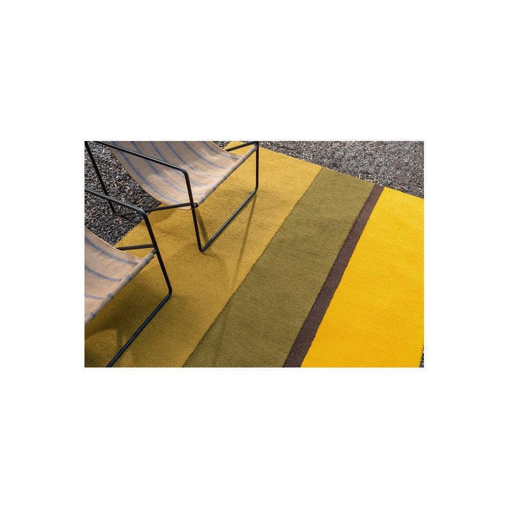 Brink & Campman Habitat Festival Stripe Yellow Outdoor Rug featuring bold yellow, mustard, olive & brown stripes on gravel background, outdoor-friendly polypropylene