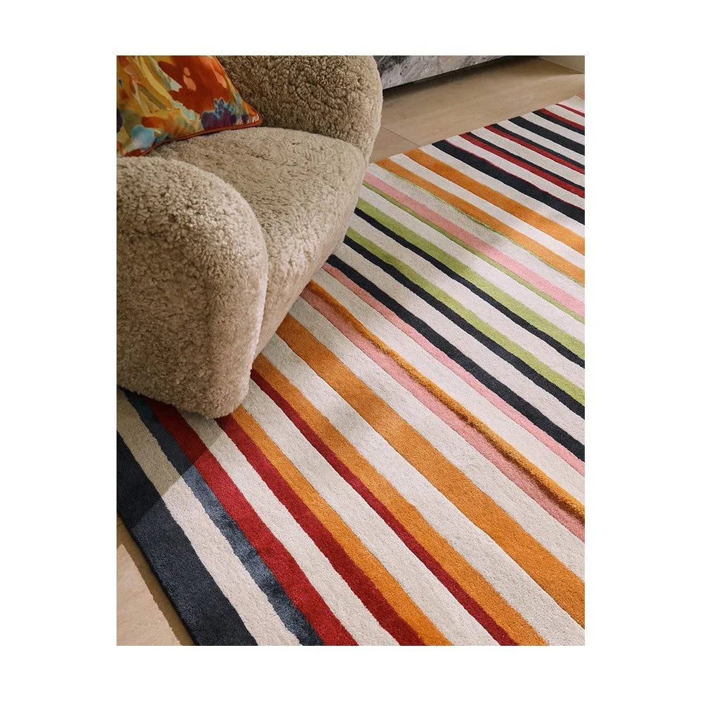 Harlequin Calla rug featuring striped pattern in red, orange, pink, lime, navy and cream on ivory background, hand-tufted wool