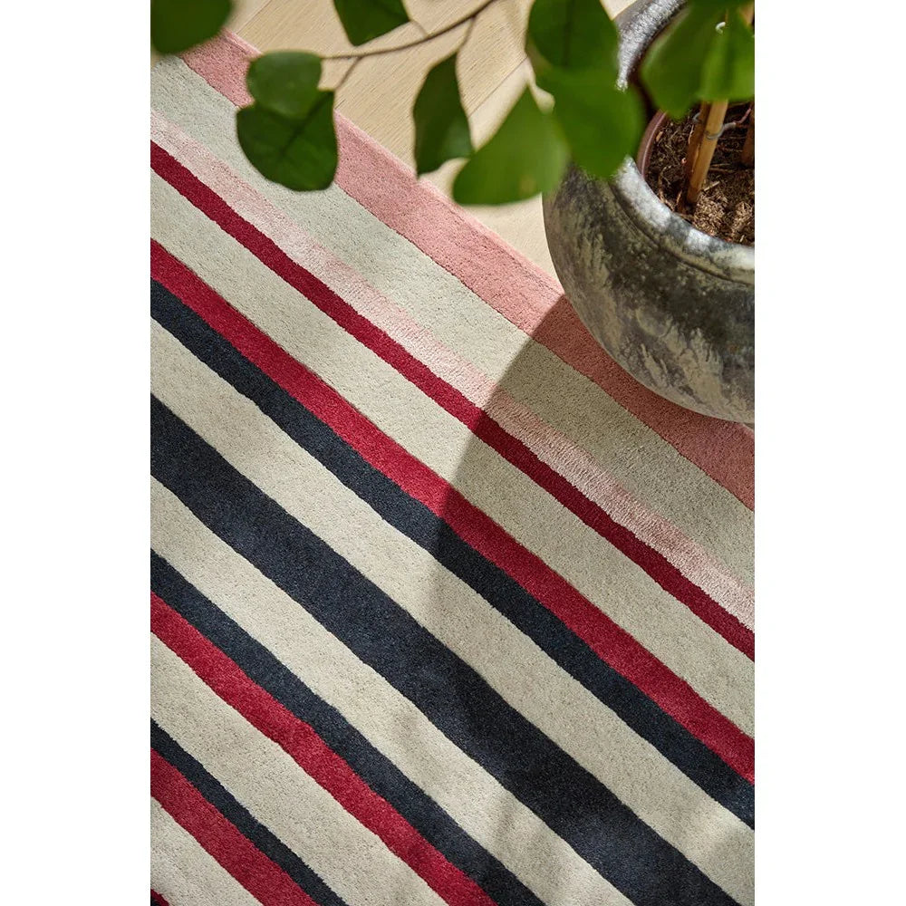 Harlequin Calla Designer Rug featuring striped pattern in cream, beige, pink, red, navy and black on light beige background, hand-tufted wool