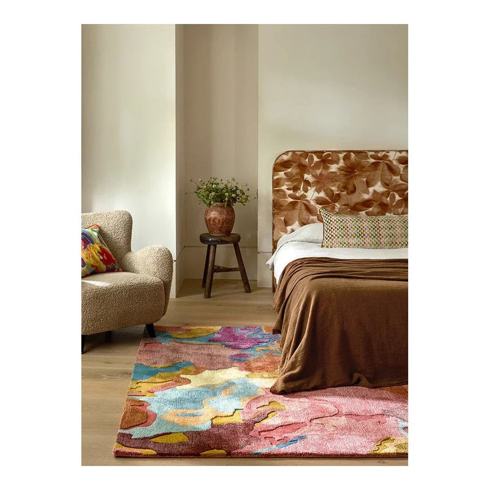 Harlequin Foresta Rosewood/huckleberry Designer Rug featuring abstract floral pattern in rosewood, pink, blue, yellow on light wood floor, hand-tufted wool