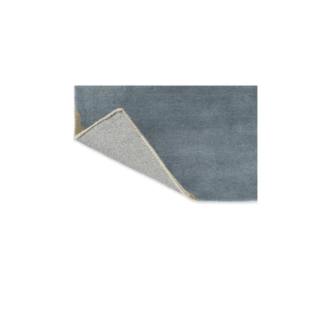 Harlequin Sumi Reflect rug featuring solid blue-grey field in cornflower and spice tones on light beige backing, hand-tufted wool