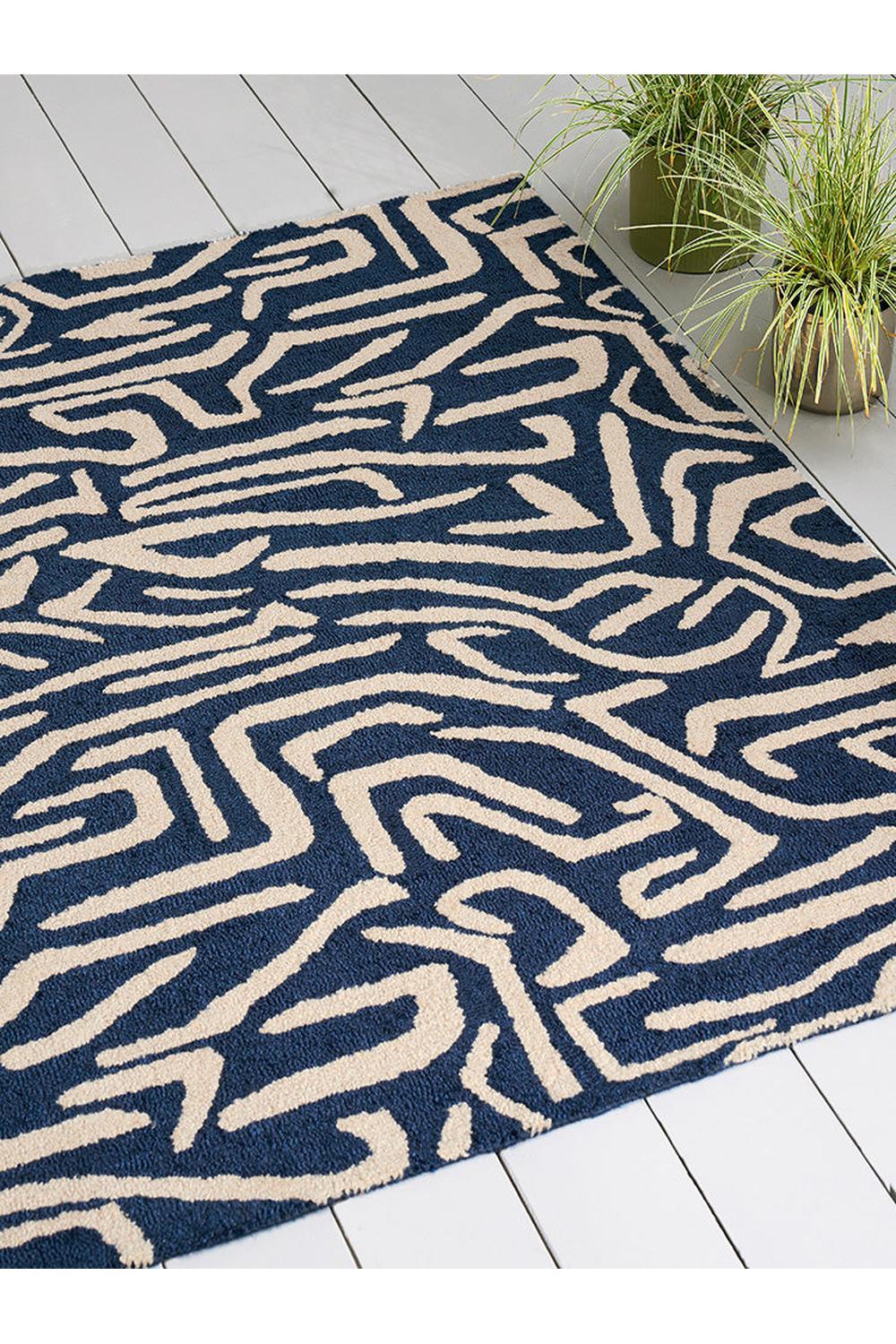 Harlequin Melodic Blue Designer Outdoor Rug featuring abstract geometric maze in navy blue and cream on pale background, outdoor rug