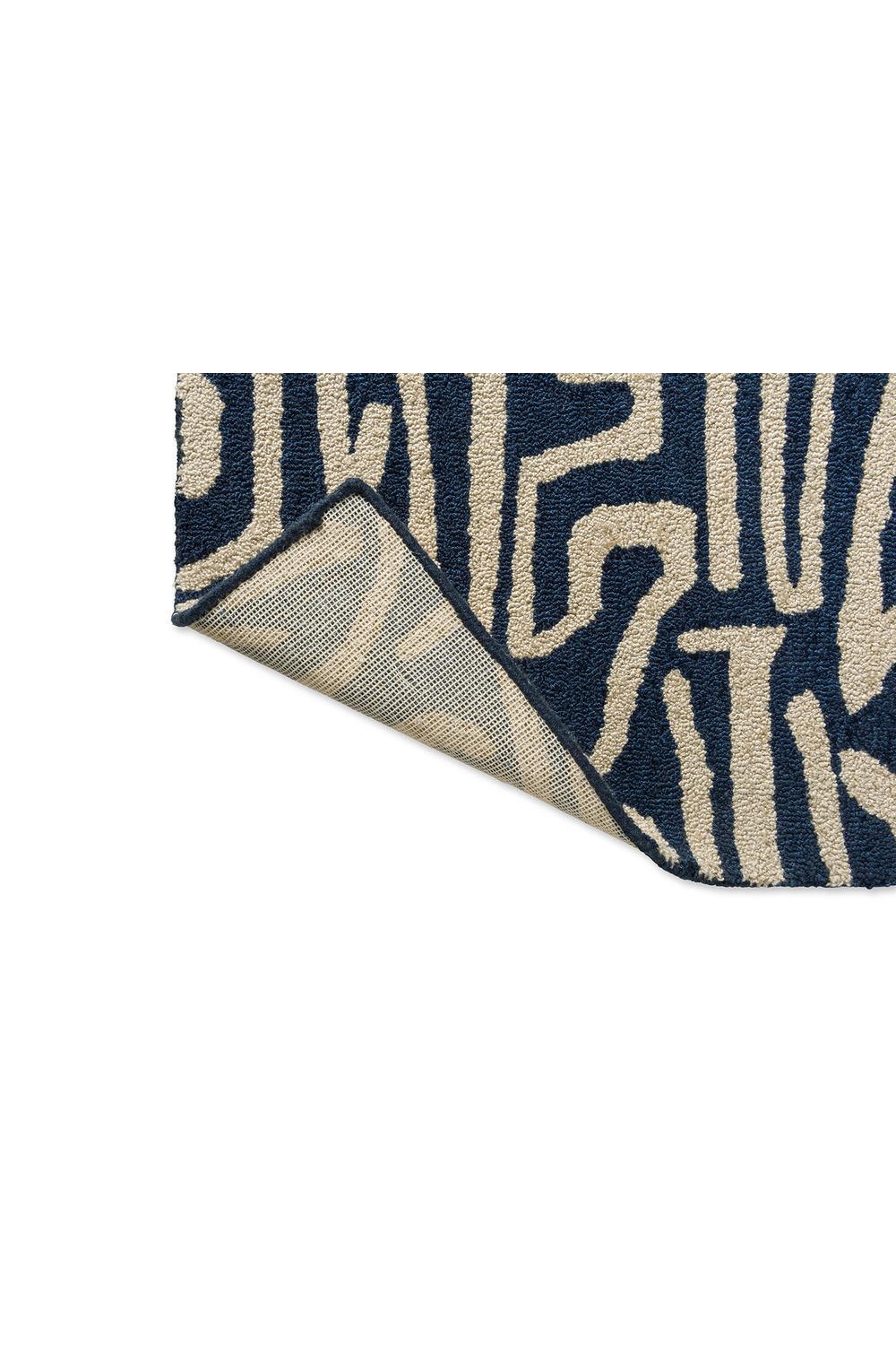 Harlequin Melodic Blue outdoor rug featuring abstract pattern in navy, beige and cream on sand background, machine-woven polypropylene
