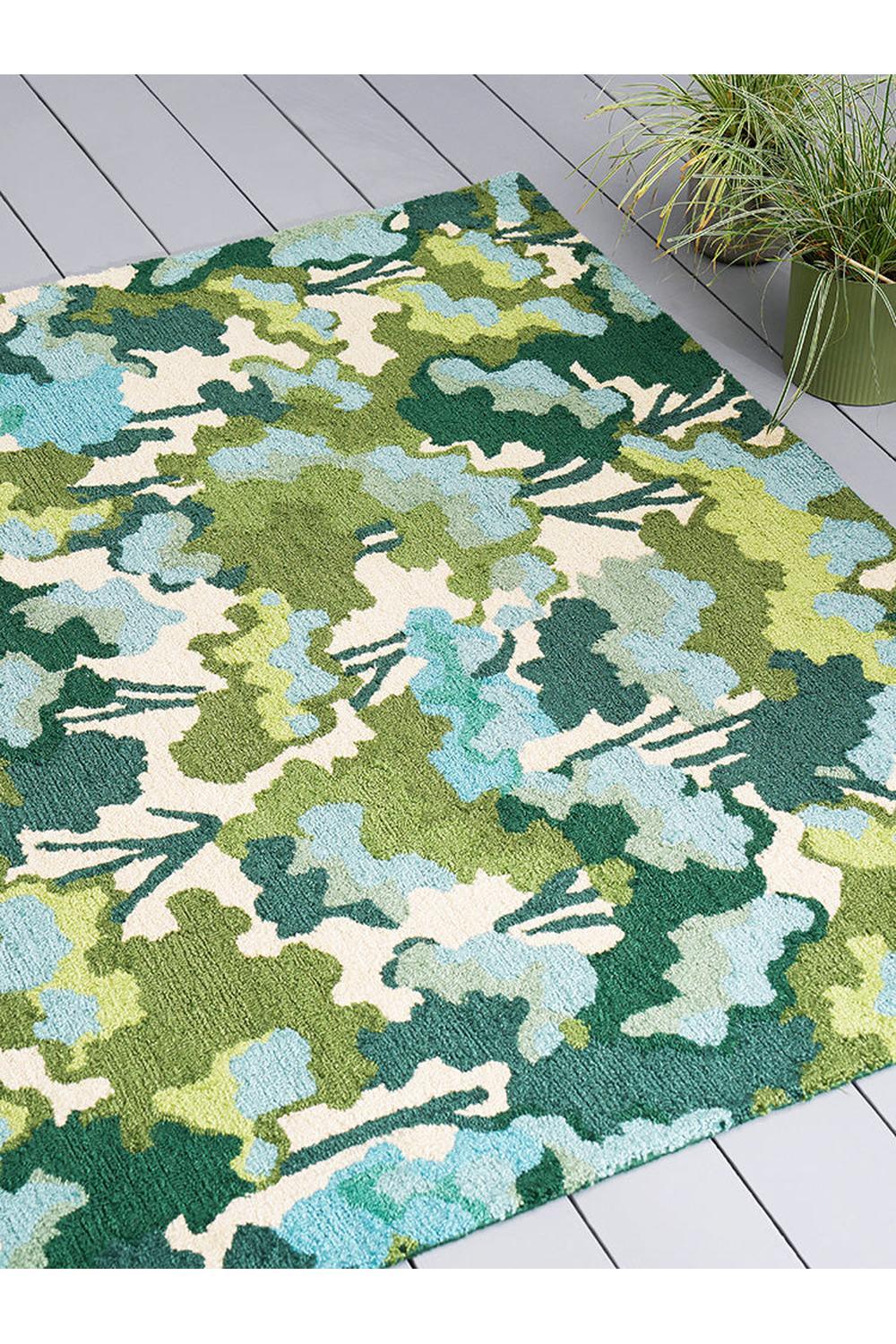 Harlequin Tree Tops Green Designer Outdoor Rug featuring abstract leaf pattern in emerald green, sage green, teal, sky blue and cream on beige background, machine-woven polypropylene
