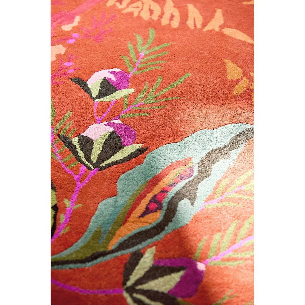 Sophie Robinson Harlequin Wonderland Floral rug featuring vibrant botanical pattern in amber, teal, pink and purple on orange background, hand-tufted wool