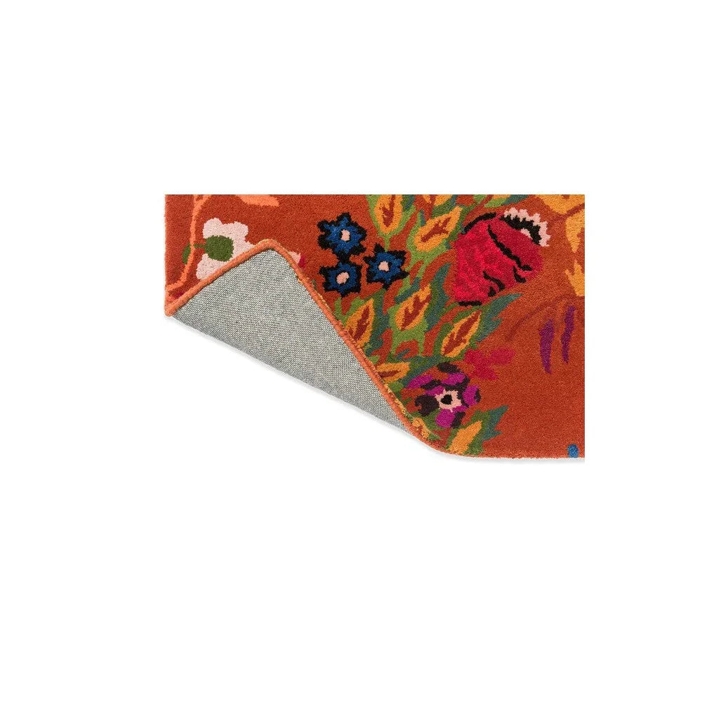 Sophie Robinson x Harlequin Wonderland Floral rug featuring vibrant floral pattern in amber, cobalt blue, emerald green, pink on orange background, hand-tufted wool