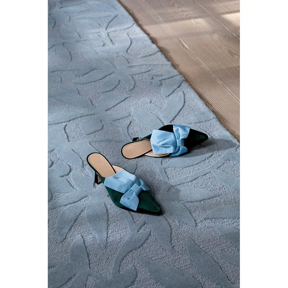 Laura Ashley Cleavers Seaspray Rug featuring leaf-patterned, wave-inspired design in light blue and sky blue on cream-beige wooden floor, hand-tufted wool