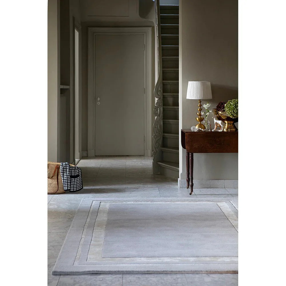 Laura Ashley Redbrook Silver Designer Rug featuring understated solid with pale border in silver-grey and cream on grey floor, hand-tufted wool