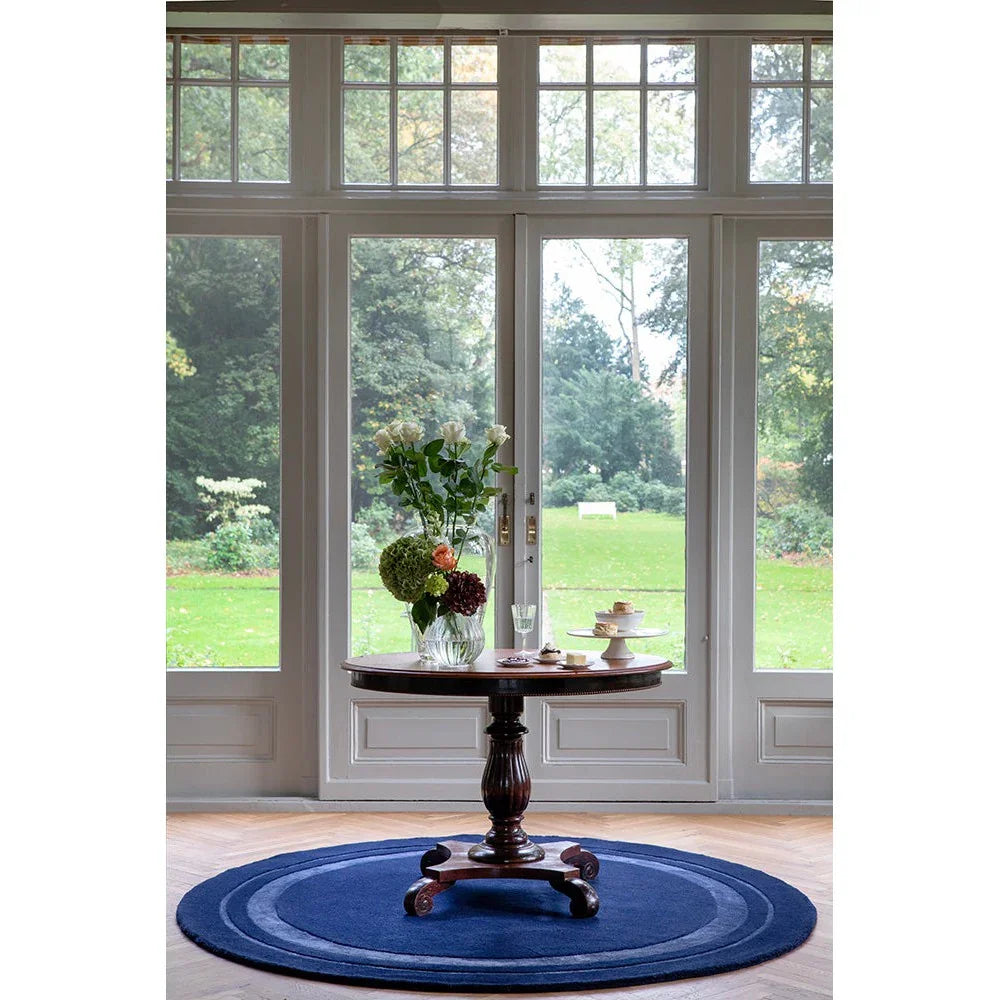 Laura Ashley Redbrook Midnight Designer Rug featuring round navy blue rug on light wood floor, hand-tufted wool