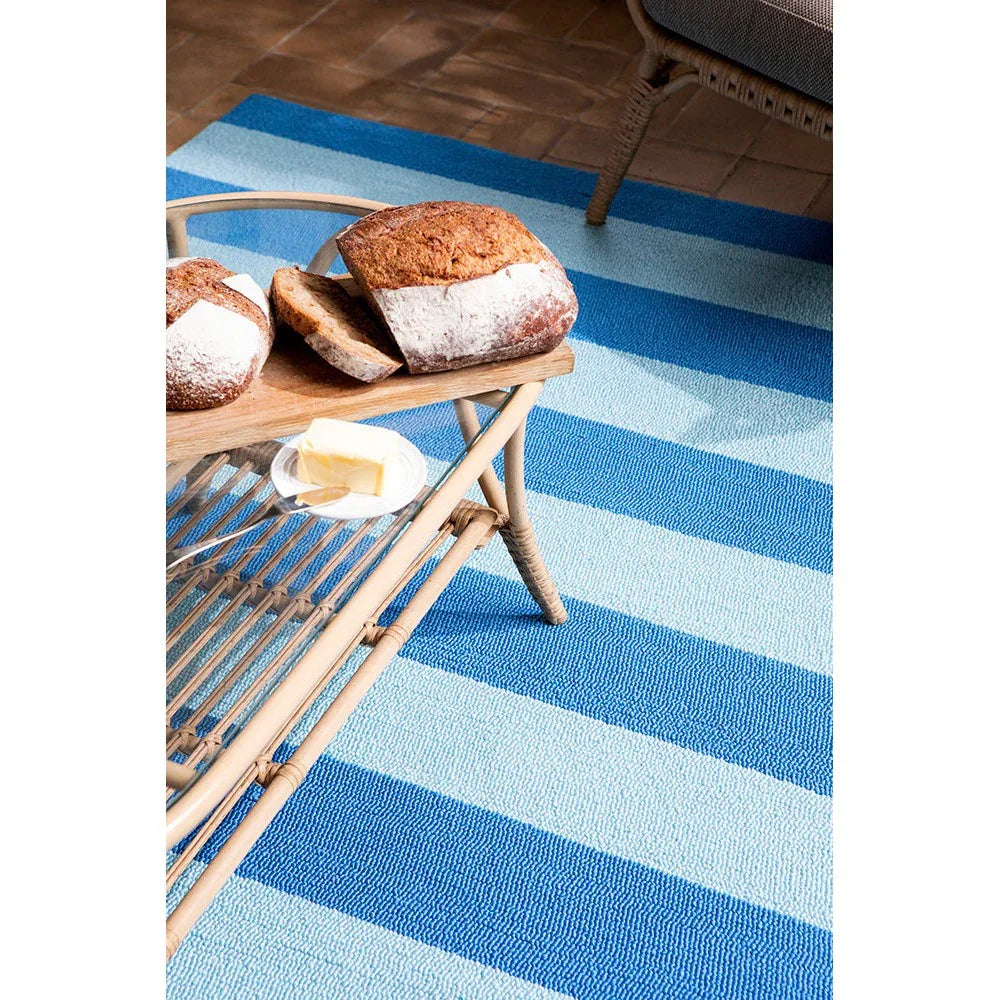 Laura Ashley Lille Sky Blue Outdoor Designer Rug featuring striped pattern in sky blue, light blue and royal blue on patio, machine-woven outdoor rug