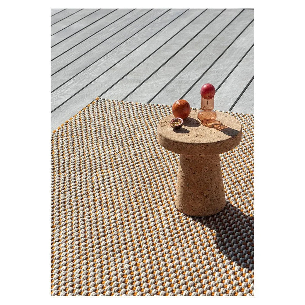 Brink & Campman Lace outdoor rug featuring woven dot pattern in white, ivory, mustard on grey deck, power-loomed polypropylene