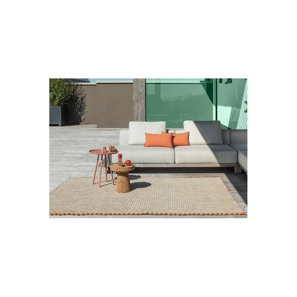 Brink & Campman Lace Tri-colo ure White Outdoor Rug featuring cream braided border with orange accents on wooden deck, machine-woven polypropylene