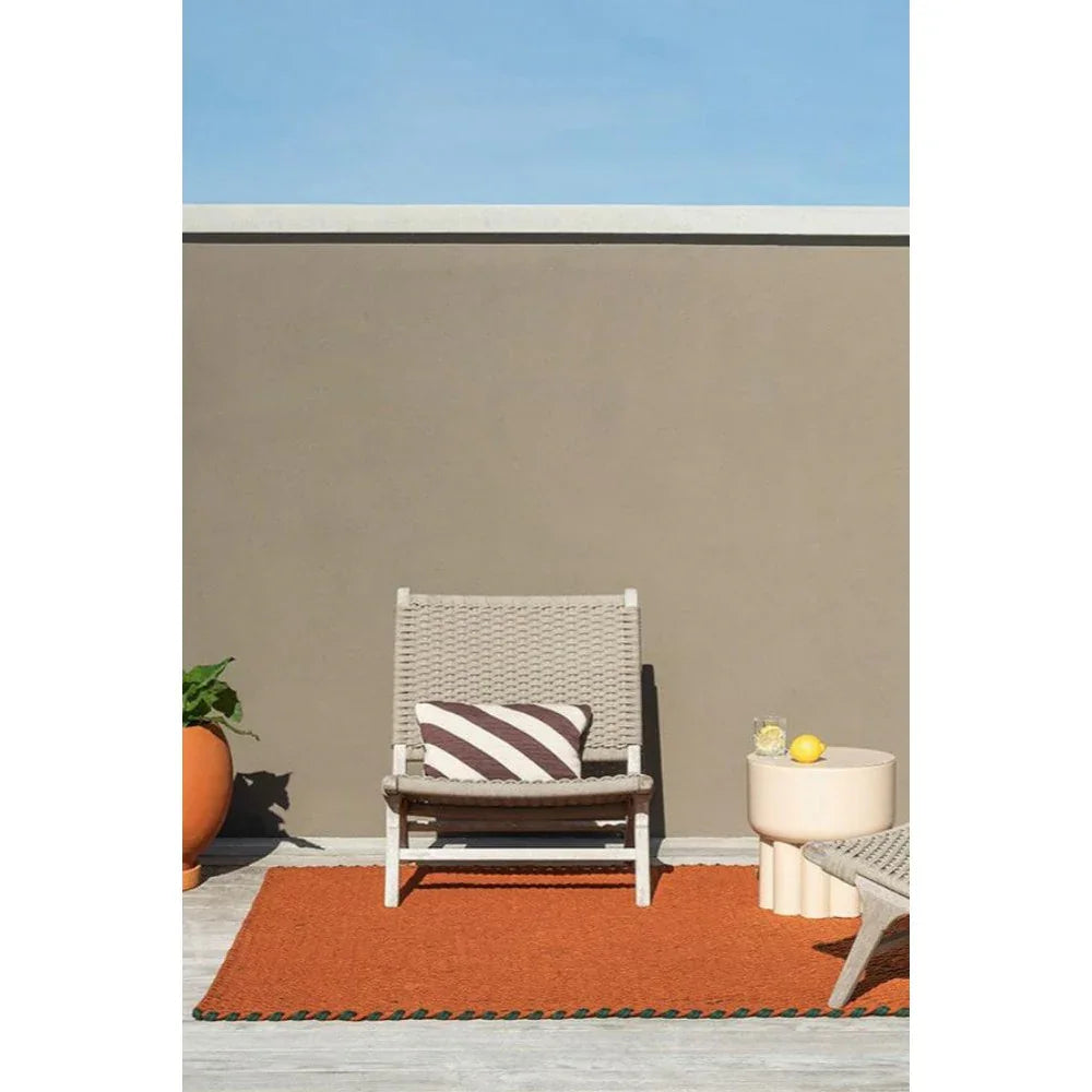 Brink & Campman Lace Tri-coloure Terra Outdoor Designer Rug featuring burnt orange with green edge on beige patio, hand-woven polypropylene