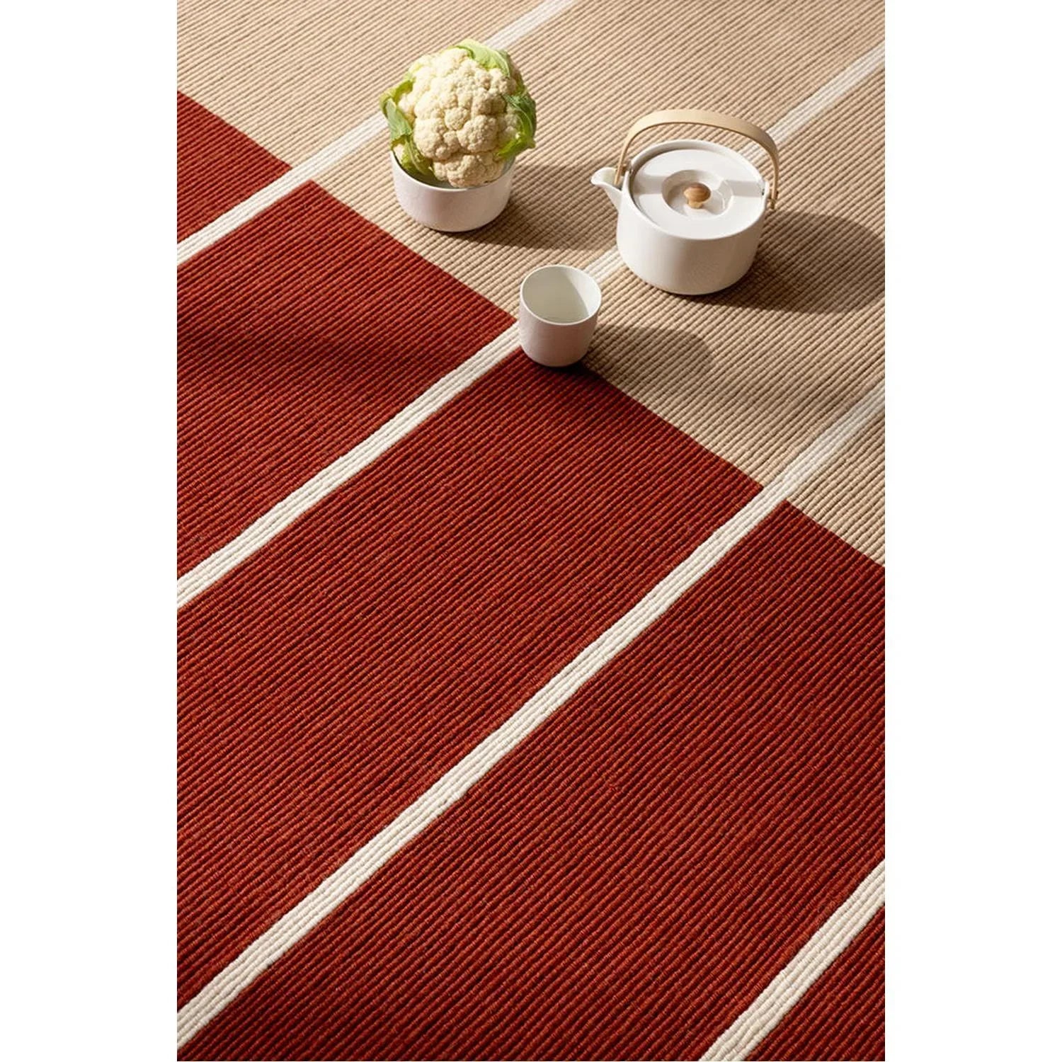 Marimekko Tiibet Burnt Orange rug featuring bold striped pattern in burnt orange, cream and beige on tan background, hand-tufted wool by Brink & Campman