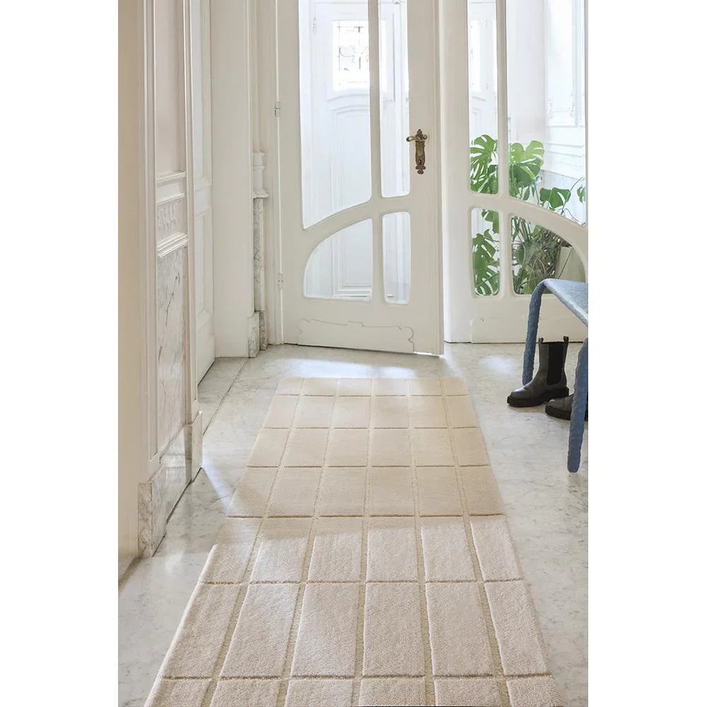 Marimekko Tiiliskivi Rug featuring grid tile pattern in natural white, cream and beige on white floor, hand-tufted wool