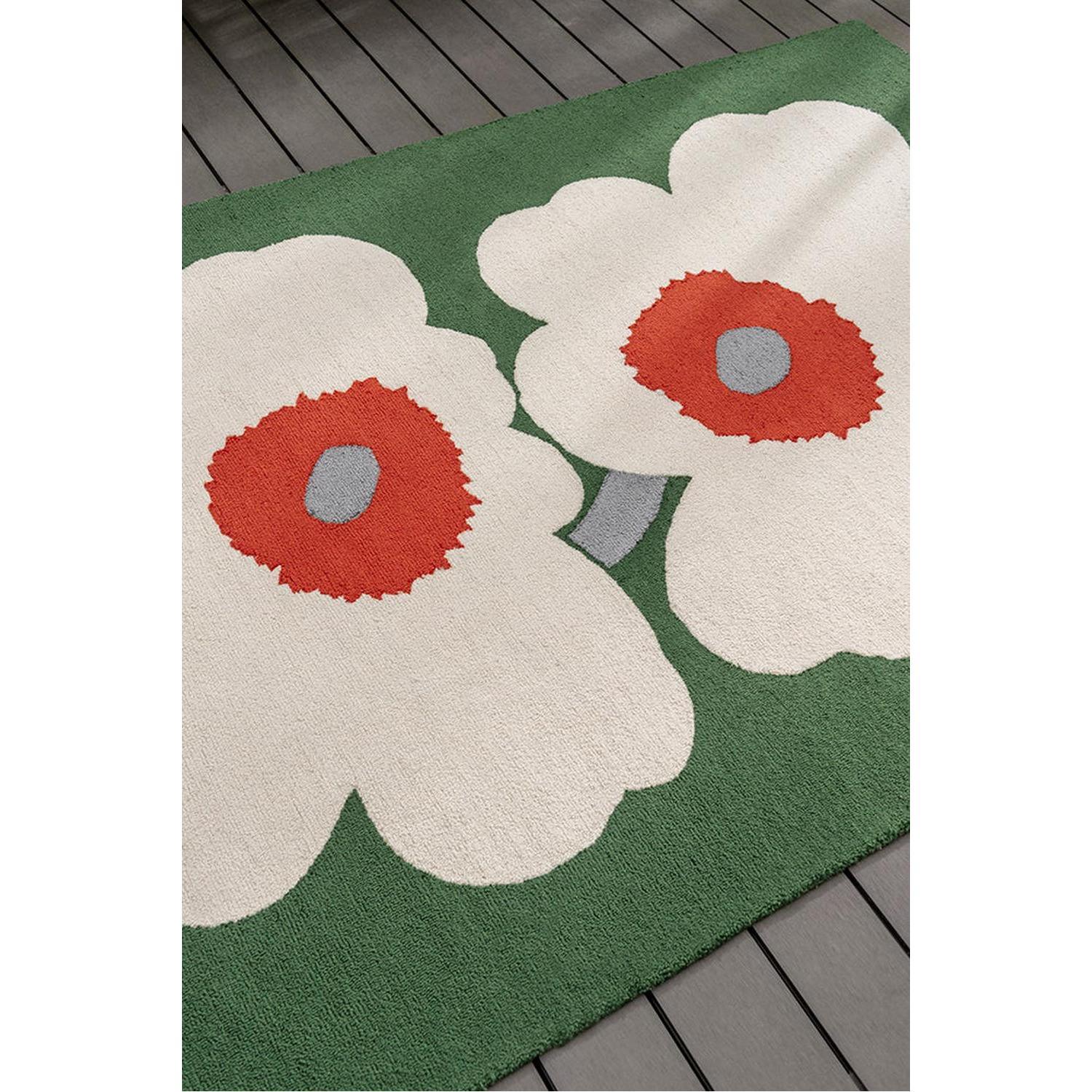 Marimekko Unikko 60th Anniversary Green rug featuring large white flowers with red centres and grey cores on emerald-green background, hand-tufted wool