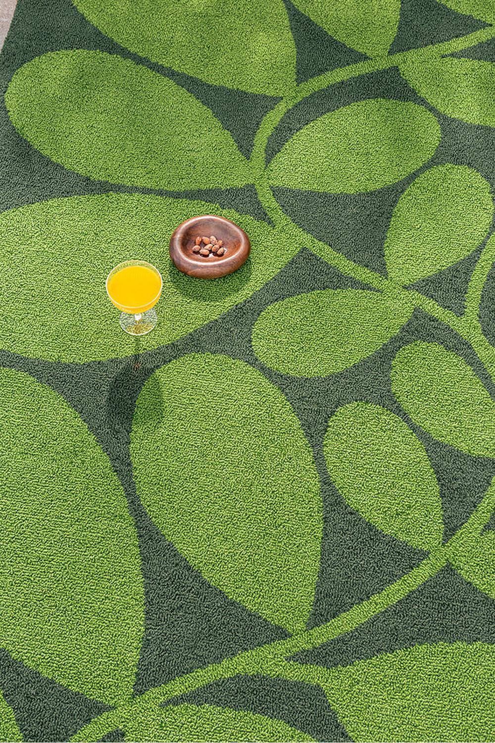 Orla Kiely Sycamore Dill outdoor rug featuring leaf pattern in lime green, chartreuse and olive on dark green background, machine-woven polypropylene