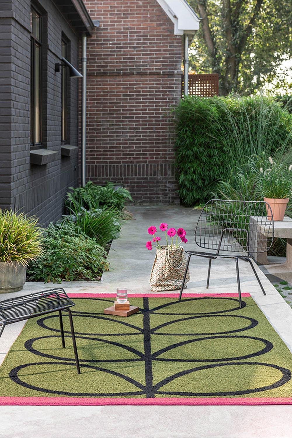 Orla Kiely Linear Stem Olive Outdoor Rug featuring olive green and black stem pattern with pink border on light background, outdoor woven rug