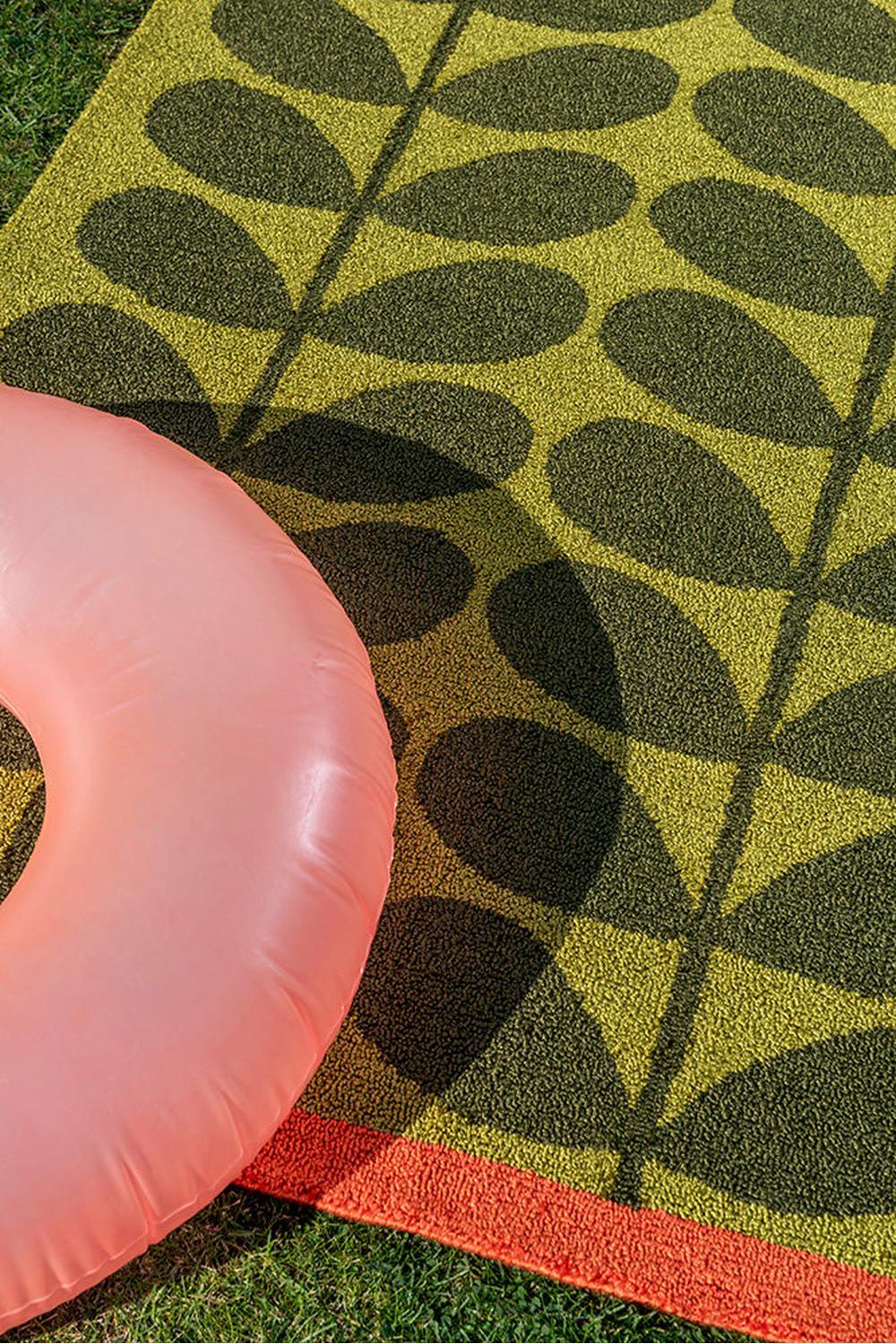 Orla Kiely Stem Seagrass Outdoor Rug featuring leaf motif in lime green, olive, and orange on pale yellow background, handwoven seagrass