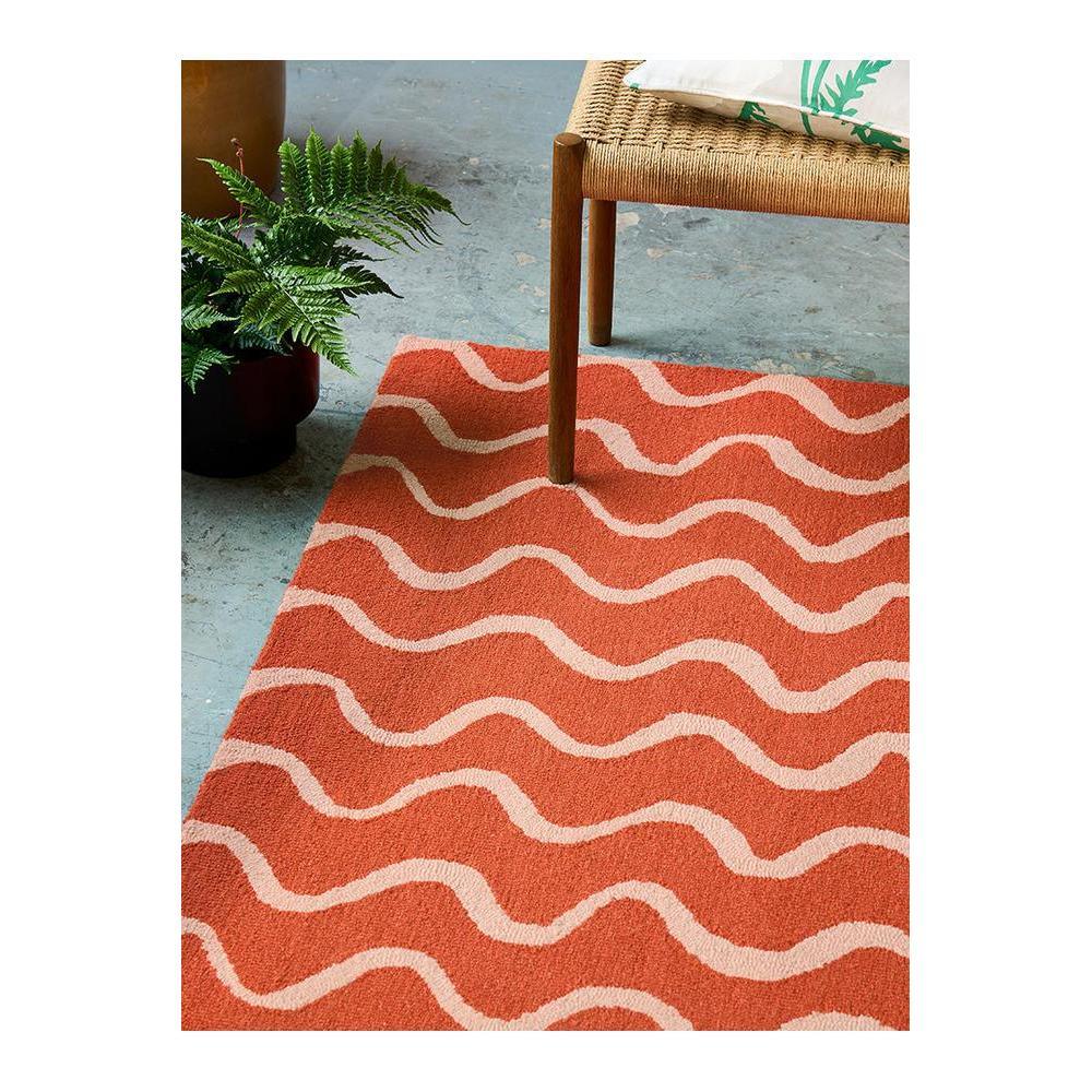 Scion Ribbon - Coral designer rug featuring wavy stripe pattern in coral and cream on light grey floor, hand-tufted wool