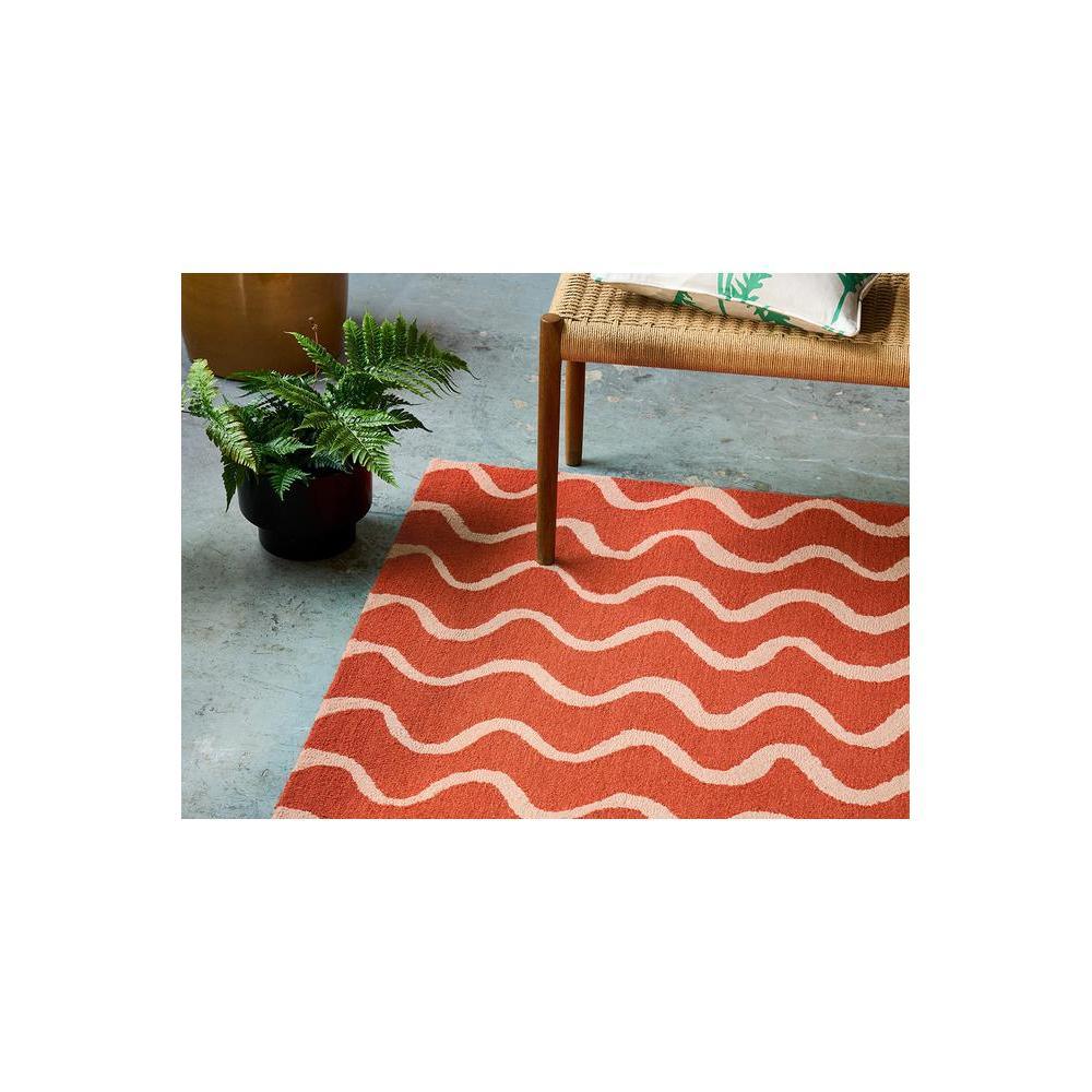 Scion Ribbon - Coral Designer Rug featuring wavy ribbon pattern in coral, cream and blush on grey floor, hand-woven wool