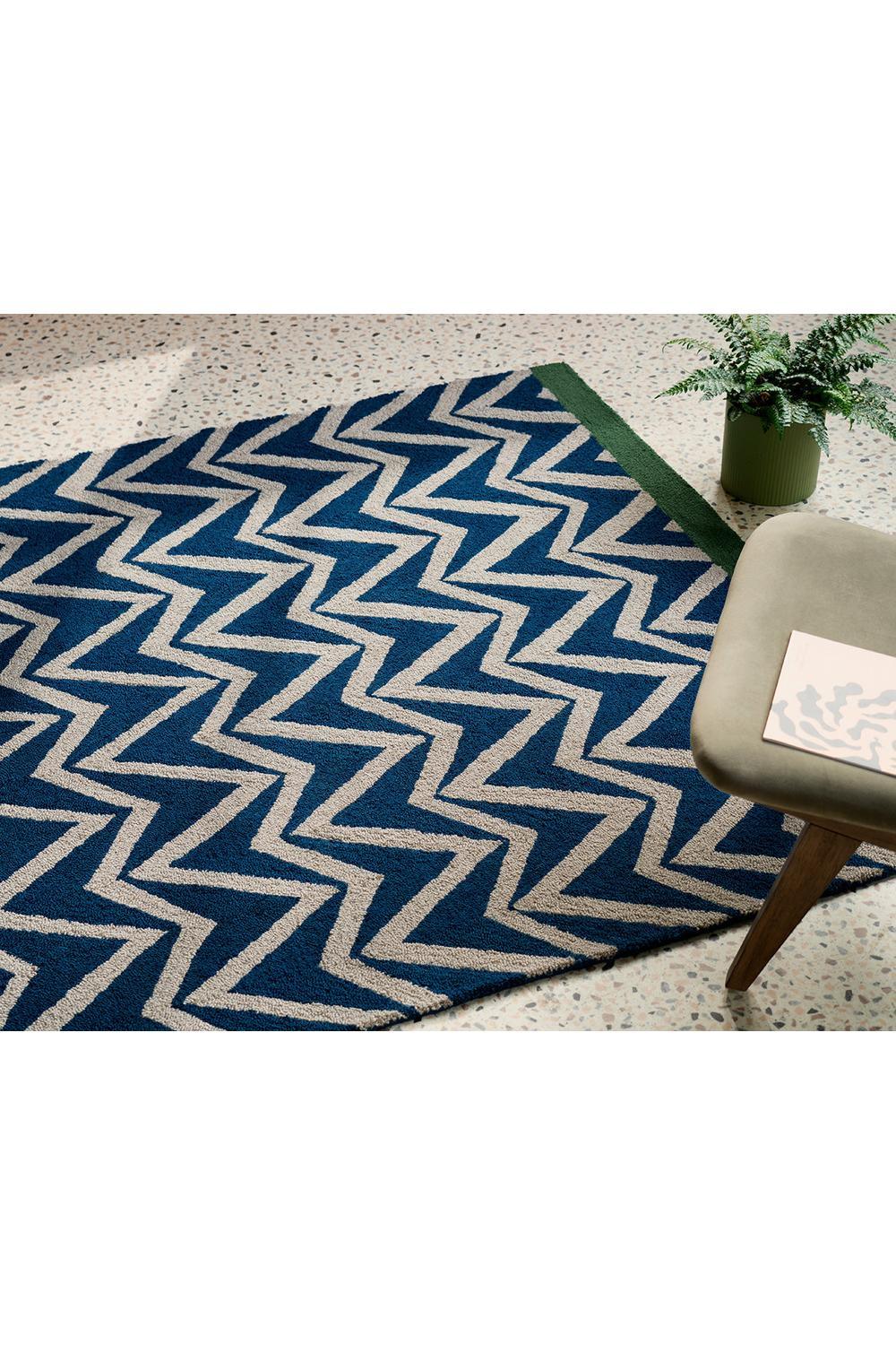 Scion Dhurrie Blue Outdoor Rug featuring chevron zigzag in navy, royal blue, beige with green edge on light terrazzo background, flatwoven polypropylene