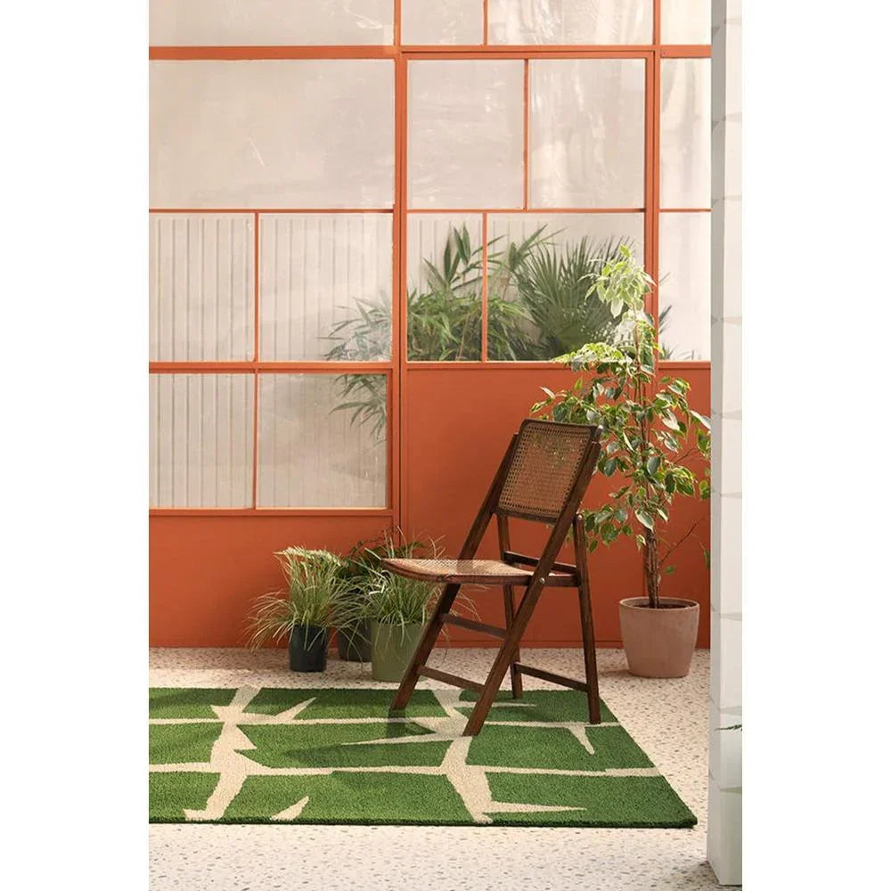 Scion Moqui Green Outdoor Rug featuring geometric leaf pattern in emerald, olive and cream on light beige terrazzo floor, power-loomed polypropylene