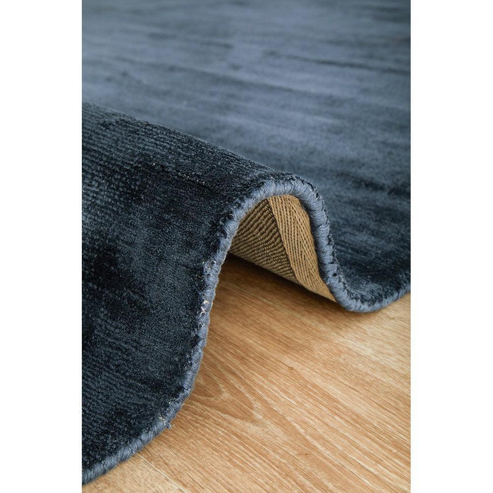 Joy Denim Rug featuring solid denim blue pile in navy and steel blue on natural wood background, machine-made cotton blend
